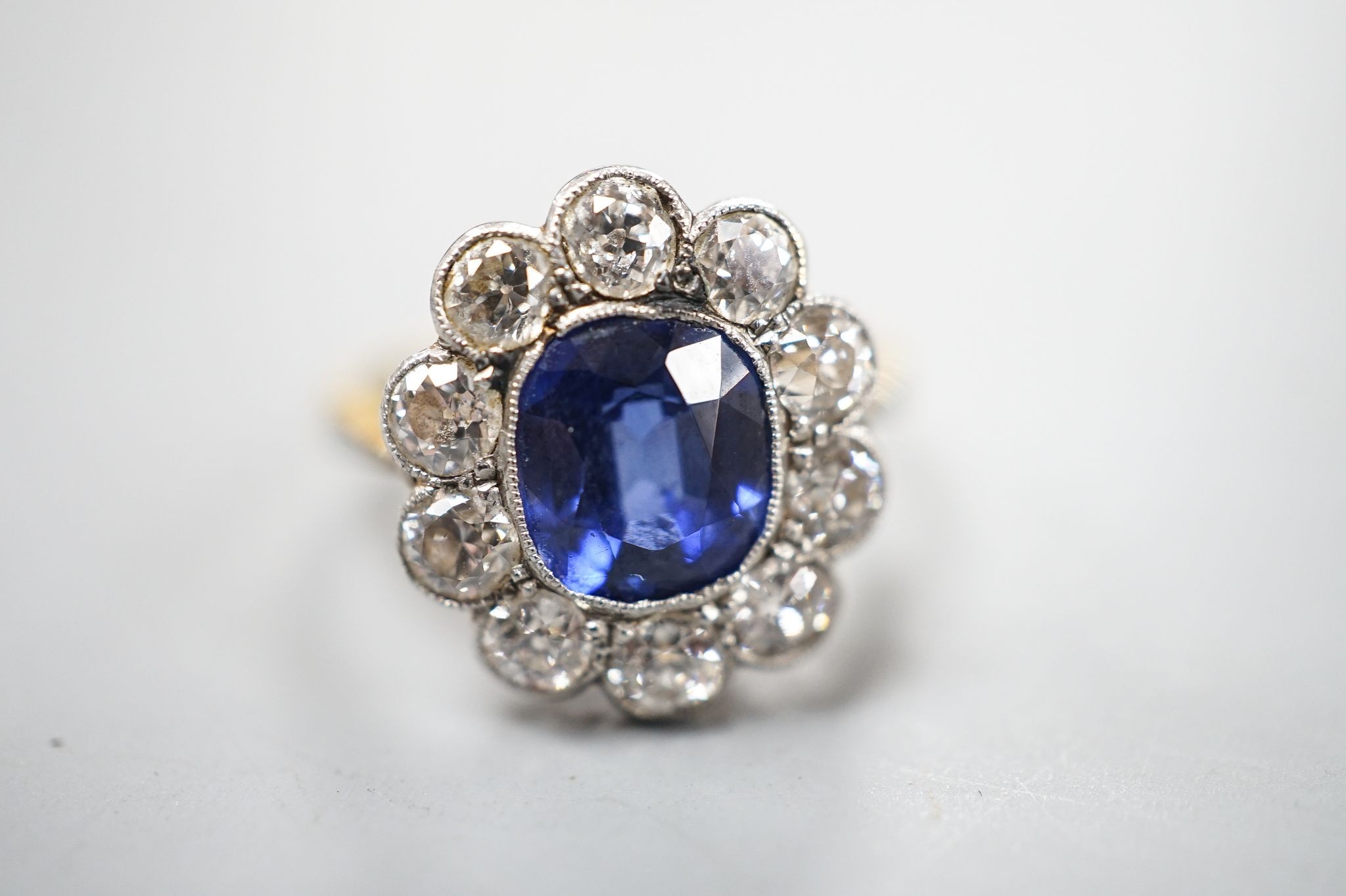 An 18ct gold and platinum, synthetic sapphire and diamond set oval cluster ring